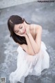 A woman in a white dress sitting on the ground.