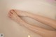 A woman's feet in a bathtub with foam on them.