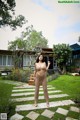 A woman standing in the middle of a lush green yard.