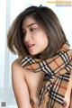 A woman wearing a plaid scarf is posing for the camera.