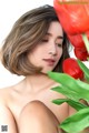 A woman sitting next to a bunch of red tulips.