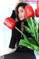 A woman sitting next to a bunch of red tulips.