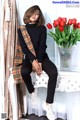 A woman sitting on a white chair next to a vase of tulips.