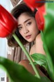 A woman sitting in front of a bunch of red tulips.