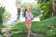 A girl with a backpack walking down a path in a park.