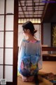 A woman in a kimono sitting on the floor in front of a window.