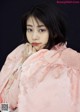 A woman in a pink kimono is posing for a picture.