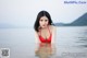 A woman in a red bikini standing in the water.