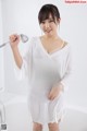 A woman in a white dress holding a shower head.