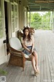 A woman sitting on a wicker chair on a porch.