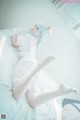 A woman in a white dress laying on a bed.