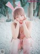 A woman in a pink bunny costume sitting on a bed of white pebbles.