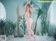 A woman in a pink lingerie posing in front of a cactus.
