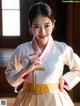 A woman in a white and pink hanbok is posing for a picture.