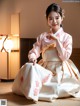 A woman in a pink and white hanbok sitting on the floor.