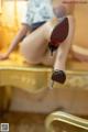 A woman sitting on top of a gold chair wearing high heels.