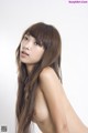 A naked asian woman with long brown hair posing for a picture.