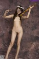 A naked woman holding a violin in her hands.