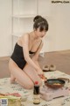 A woman in a black bathing suit cooking food on a stove.