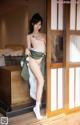 A naked asian woman standing in front of a sliding glass door.