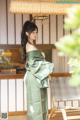 A woman in a green kimono standing in front of a window.