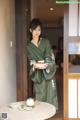 A woman in a green kimono holding a plate of food.