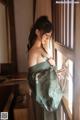 A woman in a green kimono standing by a window.