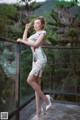 A woman in a floral dress standing on a balcony.