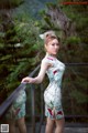 A woman in a cheongsam standing on a bridge.