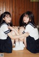 Two young women in school uniforms sitting on the floor.