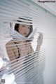 A woman standing in front of a window with blinds.