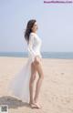 A woman in a white dress standing on a beach.