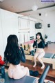 A woman sitting on a reformer in front of a mirror.