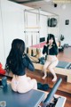 A woman sitting on a reformer in front of a mirror.