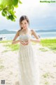 A woman in a white dress standing on a beach.