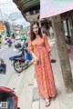 A woman in a pink dress standing on the side of a street.