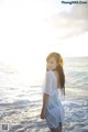 A woman standing on the beach with a flower in her hair.