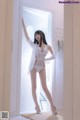 A woman in a white lingerie standing in front of a door.