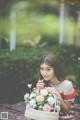 A woman holding a basket full of flowers on a bench.