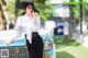 A woman in a white shirt and black hat leaning on a blue car.