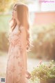 A woman in a pink dress standing next to a potted plant.