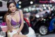 A woman in a purple bikini sitting on the hood of a car.