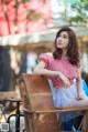 A woman sitting at a table in a red and white top.