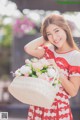 A woman in a red and white dress holding a basket of flowers.