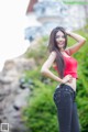 A woman in a red top and black jeans posing for a picture.