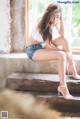 A woman sitting on a window sill with her legs crossed.