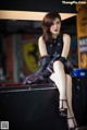 A woman in a black dress sitting on top of a table.