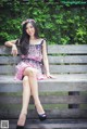 A woman sitting on a wooden bench in a park.