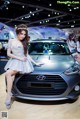 A woman in a silver dress standing next to a car.