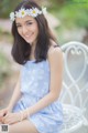 A woman in a blue dress sitting on a white chair.